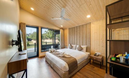 a bedroom with a bed and a large window at Glamp Wilderness in Nelamangala