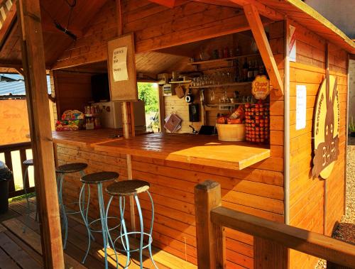 a bar in a wooden house with stools at Camping de la ferme aux ânesses, mobil home myrtille in Bressuire