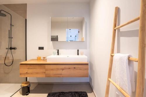 La salle de bains est pourvue d'un lavabo et d'un miroir. dans l'établissement Prachtig appartement met zwembad en fitness, à Ostende