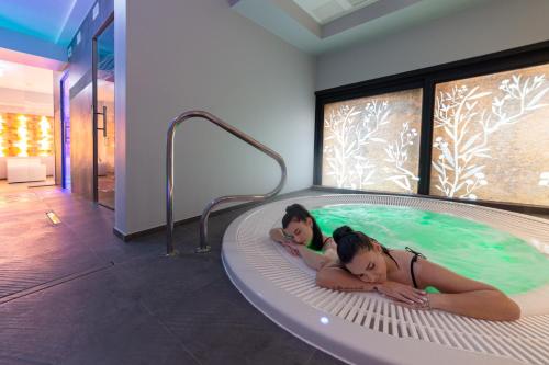 two girls laying in a hot tub in a room at Hotel Alexander in Cattolica