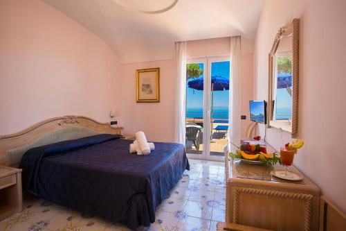 a bedroom with a bed and a view of the ocean at Hotel Terme Cristallo Palace & Beach in Ischia