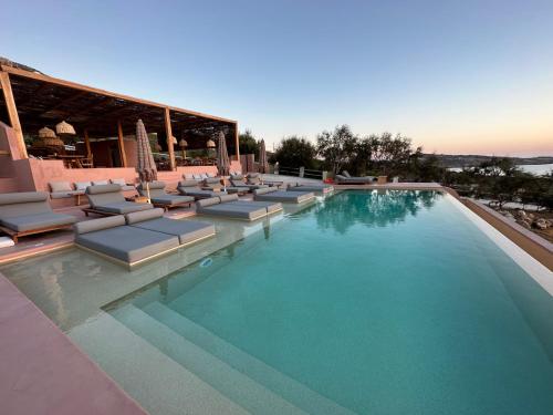 a large swimming pool with lounge chairs at Akre Hotel - Designed for Adults in Naxos Chora