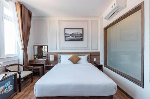 a bedroom with a white bed and a large screen at PINE VIEW Hotel Dalat in Da Lat