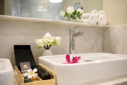 a bathroom with a white sink with flowers and towels at Memoire Palace Resort & Spa in Siem Reap