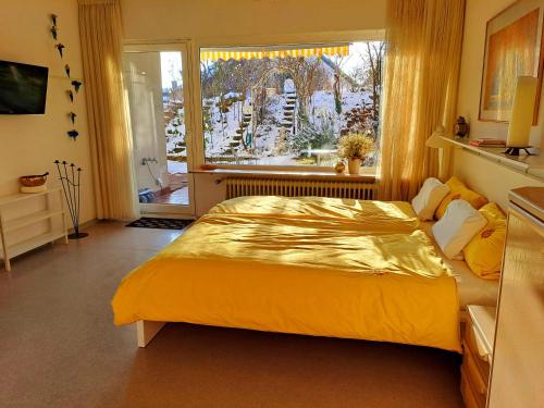 - une chambre avec un grand lit jaune et une fenêtre dans l'établissement Wohlfühl & Wellness Oase, à Neustadt an der Weinstraße
