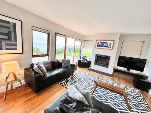 a living room with a black leather couch and a tv at Sea Haven · Tranquil Costal Retreat in Youghal