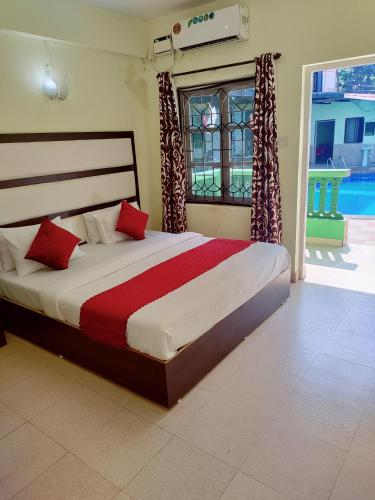 a bedroom with a large bed with red pillows at JV HOLIDAY HOME CANDOLIM in Candolim