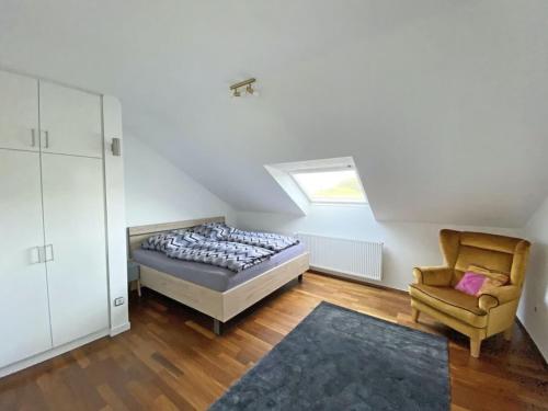um quarto com uma cama, uma cadeira e uma janela em Ferien am Königshof em Georgsmarienhütte