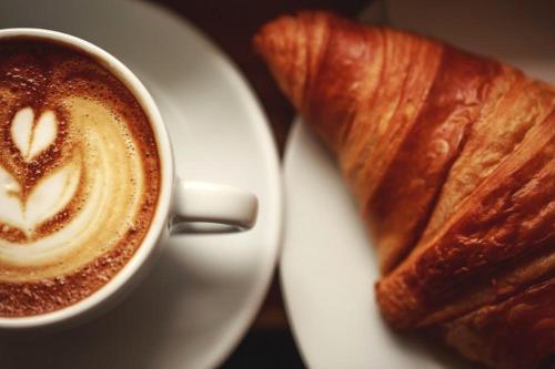 een kop koffie en een croissant op een bord bij Residenza Giancesare Family Apartments in Paestum