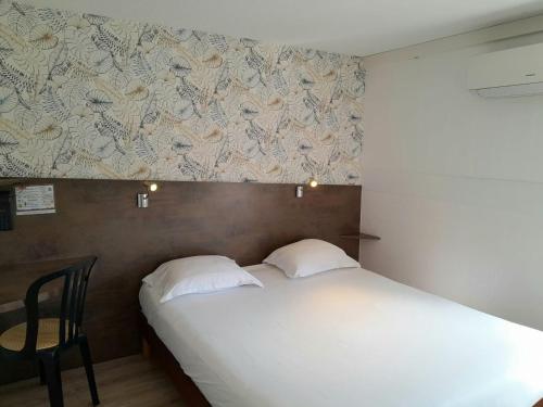 a bedroom with a bed and a desk and a wall at Fasthotel Narbonne in Narbonne