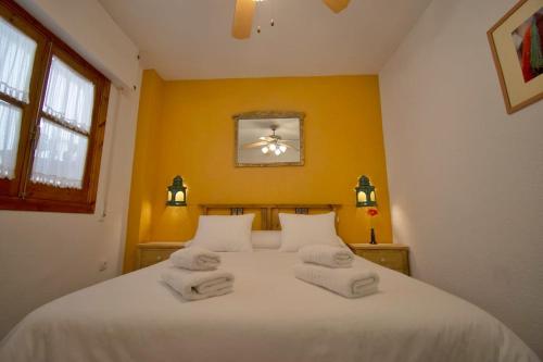 a bedroom with a white bed with towels on it at Frente a la Alhambra in Granada