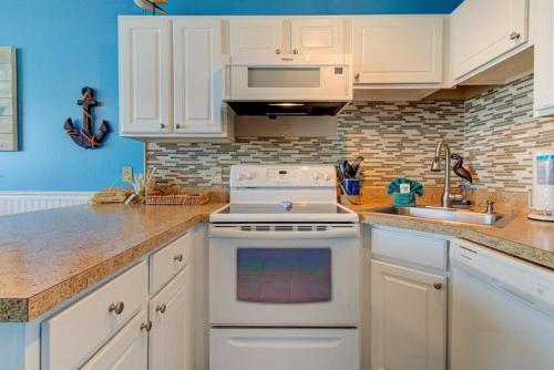 a kitchen with white cabinets and a white stove top oven at 0305 Mako Your Dreams Come True by Atlantic Towers in Carolina Beach