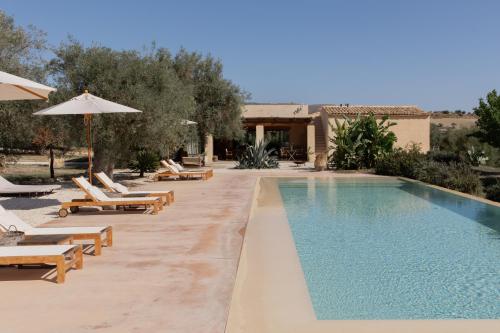 a pool with chairs and umbrellas next to a resort at IUTA Glamping & Farm in Noto