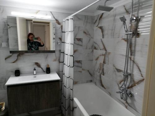 a woman taking a picture of a bathroom with a mirror at DZ Apartment AXD in Alexandroupoli