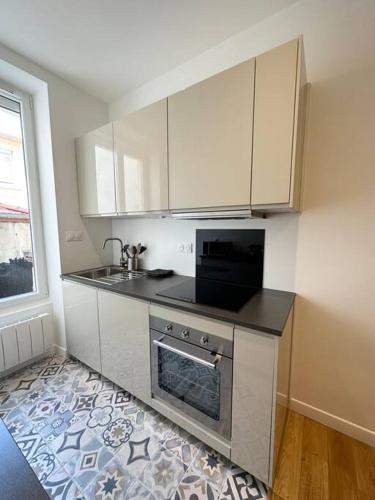 une cuisine avec des armoires blanches, un évier et une cuisinière dans l'établissement Magnifique T2 35m2 Prox Gare, à Lyon