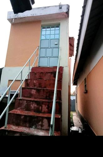 a set of stairs leading to a building with a door at Home away from Home in Kisii