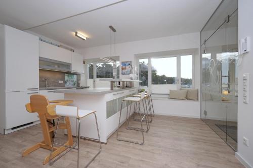 een keuken met witte werkbladen en barkrukken bij TRAUM FeWo Strandliebe mit Meerblick, 3 Schlafzimmer, 2 Bäder in Binz