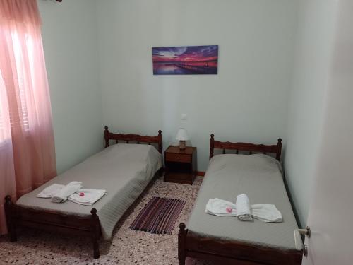 two twin beds in a room with a table at Pitsinis Apartments I in Roda