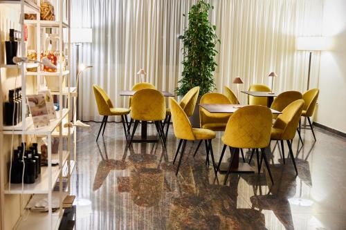 a dining room with yellow chairs and a table at Appia Antica Hotel in Corato