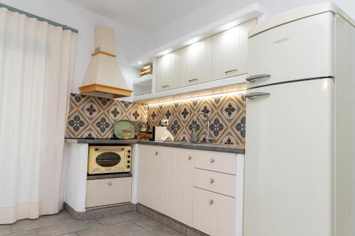 a kitchen with white cabinets and a refrigerator at Achinos By The Sea Milos in Agia Irini Milos