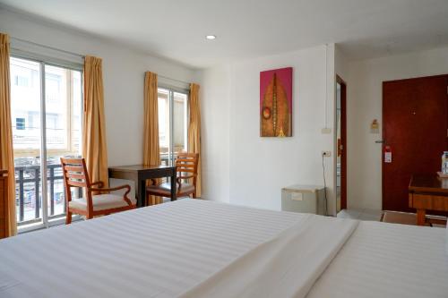 1 dormitorio con 1 cama blanca, mesa y sillas en 18 Coins Budget Hotel, en Pattaya central