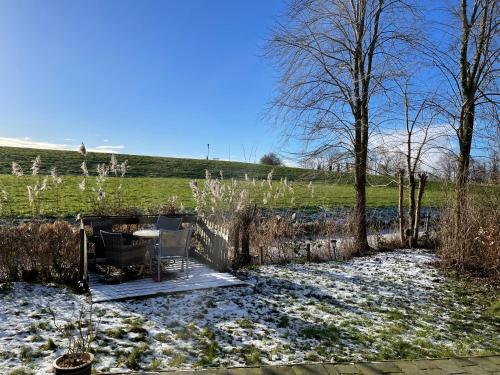 a patio with two chairs and a table in a field at Nieuwe Beachbungalow aan IJsselmeer 39 24 four seasons in Lemmer