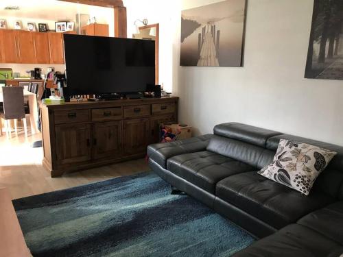 塞納河畔維特里的住宿－3 chambres/ bail mobilité possible，客厅配有黑色真皮沙发和平面电视。
