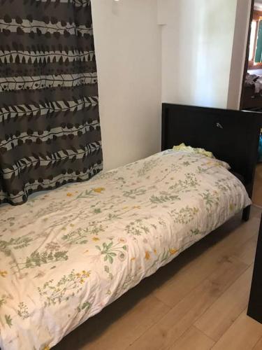 Ce lit se trouve dans une chambre dotée d'un couvre-lit avec des fleurs. dans l'établissement 3 chambres/ bail mobilité possible, à Vitry-sur-Seine