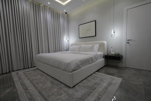 1 dormitorio blanco con 1 cama grande y cortinas en شقه فندقيه فاخرة en Riad