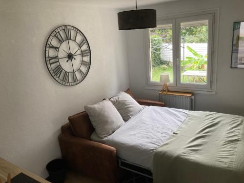 - une chambre avec un lit et une horloge murale dans l'établissement Appartement cosy, à Saint-Sébastien-sur-Loire