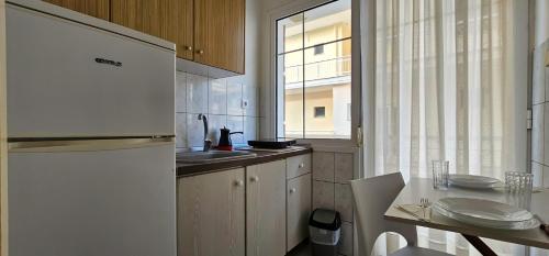 a kitchen with a white refrigerator and a table at Chariclia Hotel in Paralia Katerinis