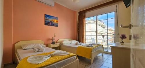a room with two beds and a window with a view at Chariclia Hotel in Paralia Katerinis