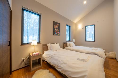 two beds in a room with two windows at Yuki Usagi - walking distance to Rusutsu Resort in Rusutsu