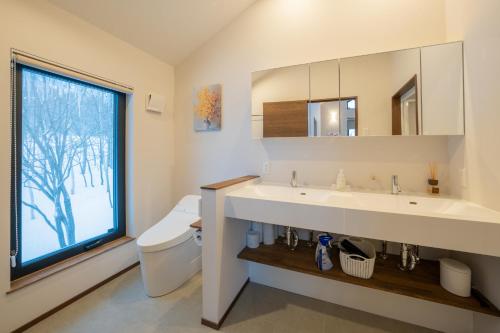 a bathroom with a sink and a toilet and a window at Yuki Usagi - walking distance to Rusutsu Resort in Rusutsu