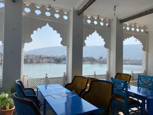 een patio met tafels en stoelen en uitzicht op het water bij Hotel Bharatpur Palace in Pushkar