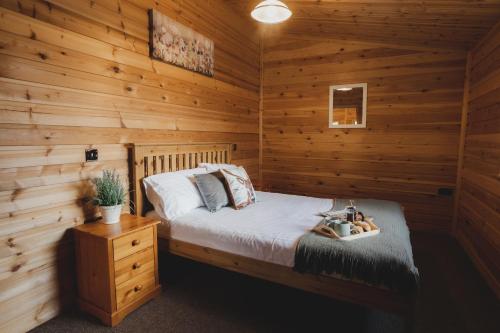 a bedroom with a bed in a log cabin at Woodlakes Park By Liv Retreats in Kings Lynn