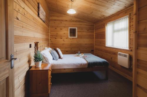 a bedroom with a bed in a wooden cabin at Woodlakes Park By Liv Retreats in Kings Lynn