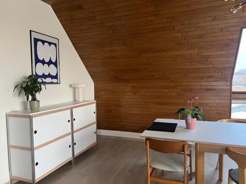 ein Esszimmer mit einem Tisch und einer Holzwand in der Unterkunft Duplex Duinenhof in Bredene