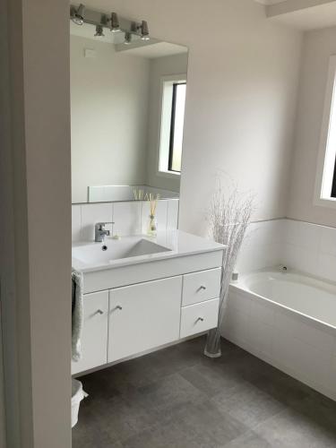 a white bathroom with a sink and a bath tub at City haven in Whanganui