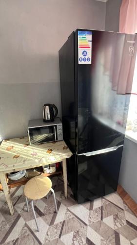 eine Küche mit einem Kühlschrank und einem Tisch mit einer Mikrowelle in der Unterkunft Квартира однокомнатная in Taras