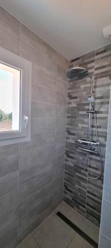 La salle de bains est pourvue d'une douche et d'un mur en pierre. dans l'établissement Appartement neuf 39m2 avec balcon à 250m de la plage, à Saint-Vincent-sur-Jard
