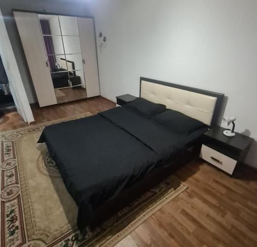 a bedroom with a black bed and a rug at Квартира однокомнатная in Taraz