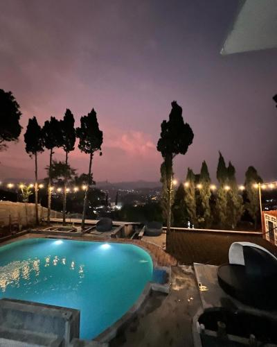 una piscina azul por la noche con árboles y luces en Villa Kaki Bukit Ciwidey, en Cisondari