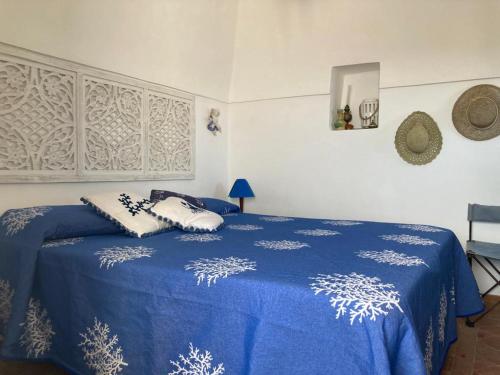 a bedroom with a blue bed with pillows on it at Dammuso Faraglione del Fico d'India in Pantelleria