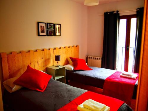 um quarto com 2 camas com lençóis vermelhos e uma janela em Las Colmenillas 1 em Tragacete