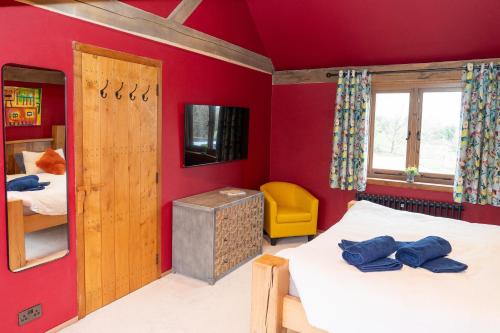 una camera da letto con pareti rosse, 2 letti e una TV di Jossie's Snug a Bletchingley