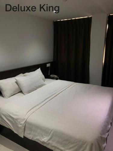 Una cama con sábanas blancas y almohadas en un dormitorio. en Hotel Vistana Micassa, en Taiping