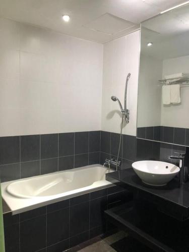 een badkamer met een bad, een wastafel en een spiegel bij Hotel Vistana Micassa in Taiping