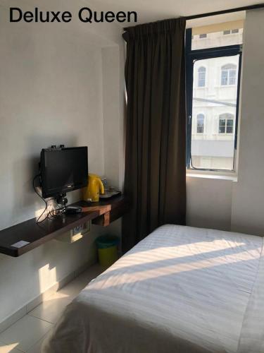 1 dormitorio con 1 cama, TV y ventana en Hotel Vistana Micassa en Taiping