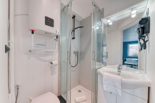 La salle de bains blanche est pourvue d'une douche et d'un lavabo. dans l'établissement Atelier-Gerland, à Lyon